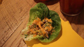Some pieces of Chicken and some sauce wrapped up in a Lettuce leaf.