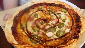 A Pizza with Barbecue Chicken, Bacon, Mozzarella, Red Onion, and Barbecue Sauce.