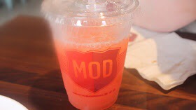 A clear plastic tub with orange beverage that's half empty.