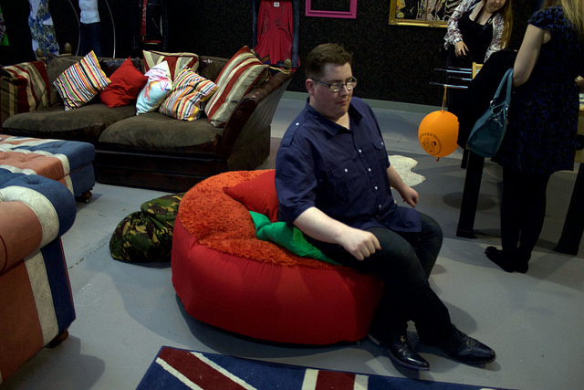 Myself wearing a dark shirt, and sitting on a red bean bag, on a medium lit background.